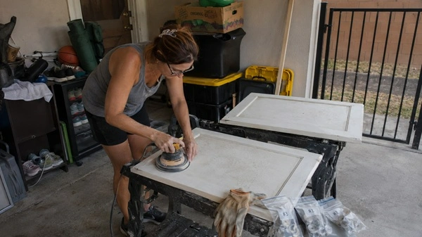 Homeowner sanding cabinet doors before applying primer.